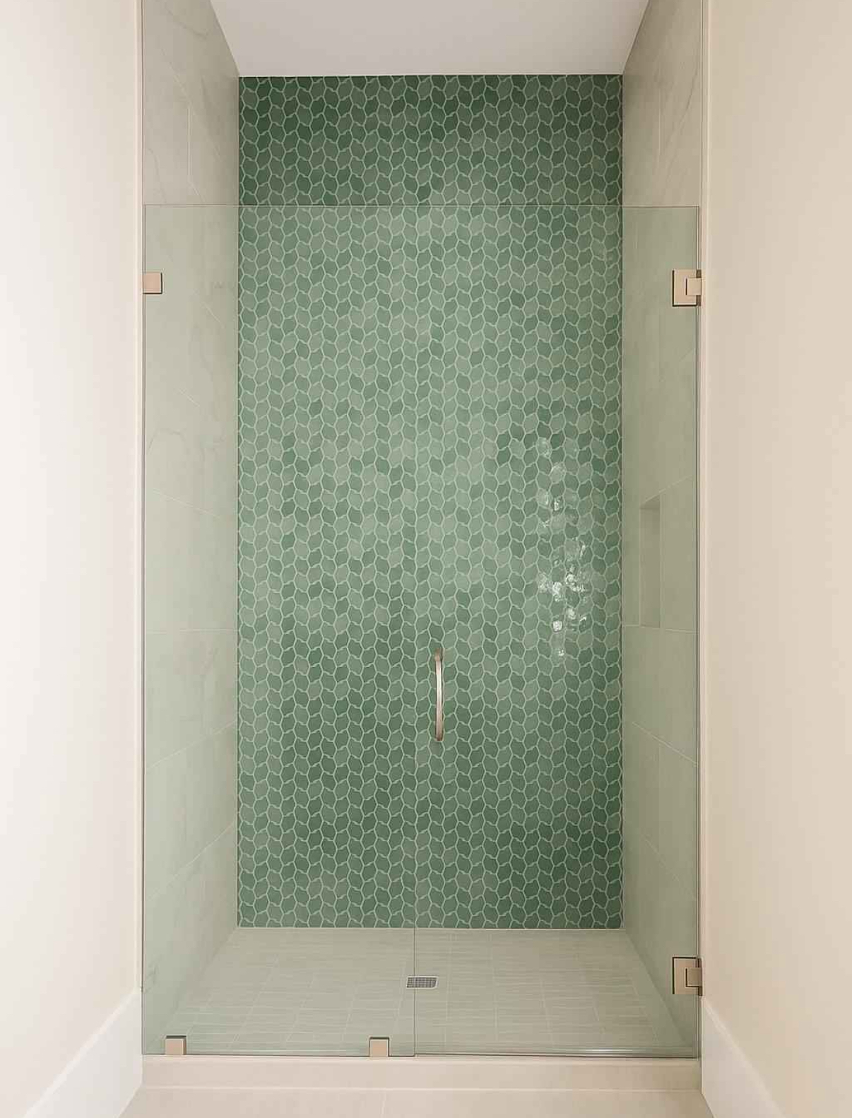 Glass-enclosed shower with a full-height green picket mosaic feature wall and light stone floor