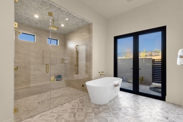 Travertine walk-in shower with mosaic ceiling, freestanding tub and patterned marble floor tile