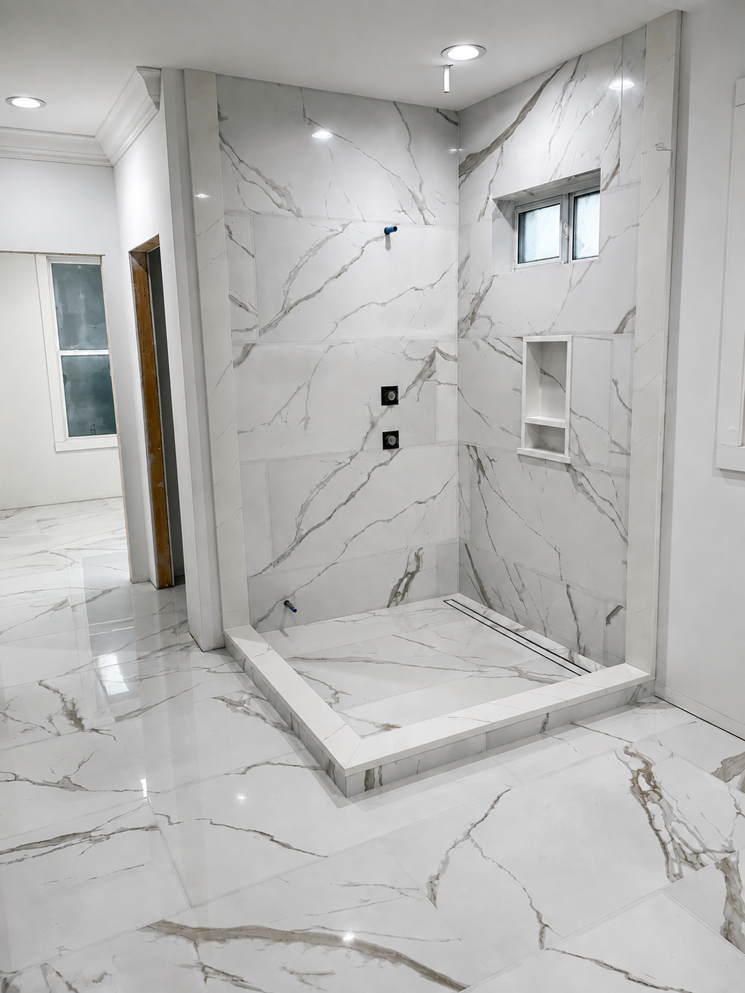 Finished curbless shower in book-matched marble-look porcelain with linear drain